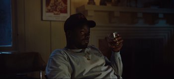 Movie still from “Nope” (2022), directed by Jordan Peele – A man sitting in a living room holding a drink; Medium shot, Over the shoulder angle