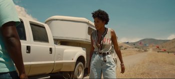 Movie still from “Nope” (2022), directed by Jordan Peele – A woman standing in front of a white truck on the side of a dirt road; Medium shot, Low angle