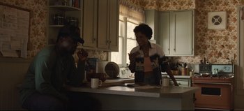 Movie still from “Nope” (2022), directed by Jordan Peele – Two people in a kitchen talking to each other; Medium shot, Over the shoulder angle