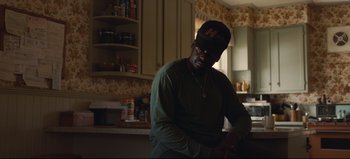 Movie still from “Nope” (2022), directed by Jordan Peele – A man sitting in a kitchen wearing a hat; Medium shot, Over the shoulder angle