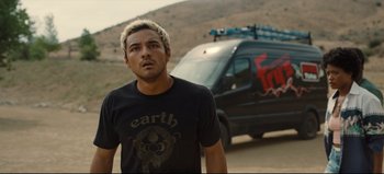 Movie still from “Nope” (2022), directed by Jordan Peele – A man standing in front of a van on the side of a dirt road; Medium shot, Over the shoulder angle