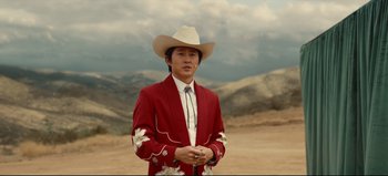 Movie still from “Nope” (2022), directed by Jordan Peele – A man wearing a cowboy hat and a red jacket; Medium shot, Over the shoulder angle