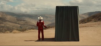 Movie still from “Nope” (2022), directed by Jordan Peele – A man in a cowboy hat stands in front of a curtain; Extreme Wide shot, Over the shoulder angle