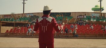 Movie still from “Nope” (2022), directed by Jordan Peele – A man wearing a cowboy hat and a red suit; Wide shot, Over the shoulder angle