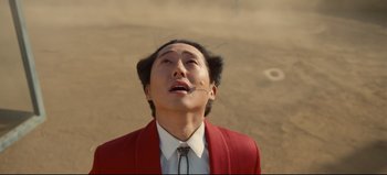 Movie still from “Nope” (2022), directed by Jordan Peele – A man in a red suit is looking up at the sky; Close Up shot, Overhead angle