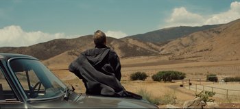 Movie still from “Nope” (2022), directed by Jordan Peele – A man sitting on the hood of a car in the desert; Wide shot, Low angle