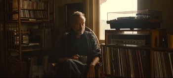 Movie still from “Nope” (2022), directed by Jordan Peele – An older man sitting in a rocking chair in front of a window; Medium shot, Low angle