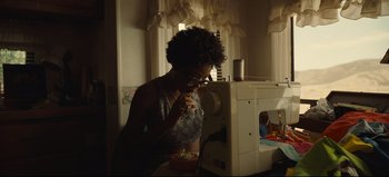 Movie still from “Nope” (2022), directed by Jordan Peele – A woman looking through a magnifying glass at something on a table; Medium shot, Low angle