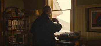 Movie still from “Nope” (2022), directed by Jordan Peele – An older man standing in front of a window; Medium shot, Over the shoulder angle