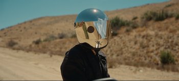Movie still from “Nope” (2022), directed by Jordan Peele – A person wearing a helmet on the side of a road; Close Up shot, Over the shoulder angle