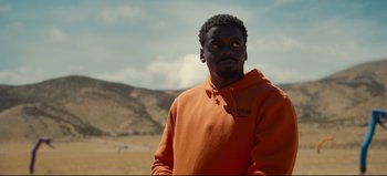 Movie still from “Nope” (2022), directed by Jordan Peele – A man in an orange hoodie standing in a field; Close Up shot, Over the shoulder angle