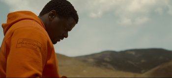 Movie still from “Nope” (2022), directed by Jordan Peele – A man in an orange shirt is looking down; Close Up shot, Low angle