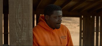 Movie still from “Nope” (2022), directed by Jordan Peele – A man in an orange hoodie standing next to a wooden pole; Close Up shot, Over the shoulder angle