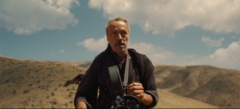 Movie still from “Nope” (2022), directed by Jordan Peele – An older man holding a camera while standing on a hill; Close Up shot, Low angle