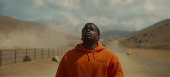 Movie still from “Nope” (2022), directed by Jordan Peele – A man in an orange hoodie looking up at the sky; Medium shot, Low angle