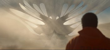 Movie still from “Nope” (2022), directed by Jordan Peele – A person standing in front of an abstract image; Medium shot, Low angle
