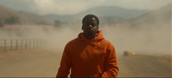Movie still from “Nope” (2022), directed by Jordan Peele – A man in an orange hoodie standing on a dirt road; Medium shot, High angle