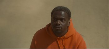 Movie still from “Nope” (2022), directed by Jordan Peele – A man in an orange hoodie stares into the camera; Close Up shot, High angle