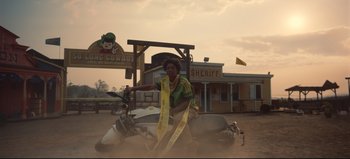 Movie still from “Nope” (2022), directed by Jordan Peele – A woman sitting on top of a motor scooter in the dirt; Wide shot, Low angle