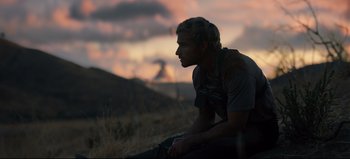 Movie still from “Nope” (2022), directed by Jordan Peele – A man sitting on the ground in a field; Medium shot, Low angle