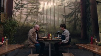 Movie still from “The End of the F***ing World” (2017), directed by Jonathan Entwistle – Two men are sitting at a table with food; Wide shot, Overhead angle
