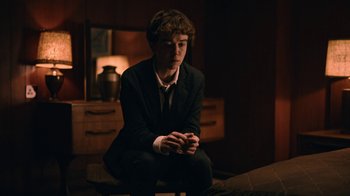 Movie still from “The End of the F***ing World” (2017), directed by Jonathan Entwistle – A man in a suit sitting on a stool; Medium shot, Over the shoulder angle