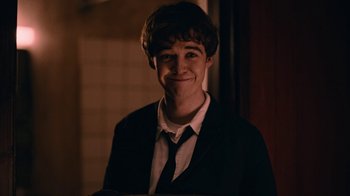 Movie still from “The End of the F***ing World” (2017), directed by Jonathan Entwistle – A man in a suit and tie smiling for the camera; Close Up shot, Over the shoulder angle