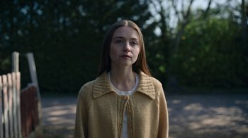 Movie still from “The End of the F***ing World” (2017), directed by Jonathan Entwistle – A woman in a yellow sweater standing in front of trees; Close Up shot, Over the shoulder angle