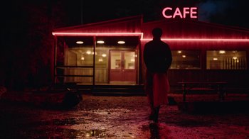 Movie still from “The End of the F***ing World” (2017), directed by Jonathan Entwistle – A person walking in front of a cafe at night; Extreme Wide shot, Low angle