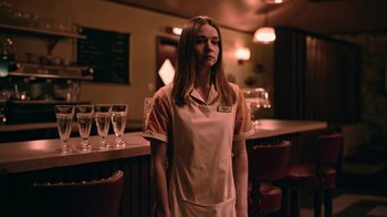 Movie still from “The End of the F***ing World” (2017), directed by Jonathan Entwistle – A woman standing in front of a bar with glasses; Medium shot, Over the shoulder angle