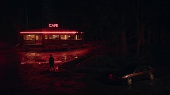 Movie still from “The End of the F***ing World” (2017), directed by Jonathan Entwistle – A person standing in front of a cafe at night; Extreme Wide shot, Over the shoulder angle