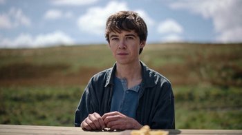 Movie still from “The End of the F***ing World” (2017), directed by Jonathan Entwistle – A young man sitting at a picnic table in the middle of a field; Close Up shot, Low angle