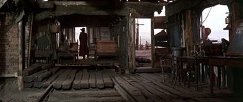 Movie still from “Once Upon a Time in the West” (1968), directed by Sergio Leone – A man standing in front of an open porch; Wide shot, Low angle
