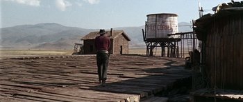 Movie still from “Once Upon a Time in the West” (1968), directed by Sergio Leone – A man walking on a wooden platform in front of a water tower; Wide shot, Low angle