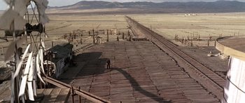 Movie still from “Once Upon a Time in the West” (1968), directed by Sergio Leone – A person standing on a platform in the middle of the desert; Extreme Wide shot, High angle
