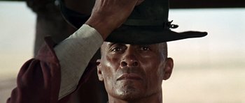 Movie still from “Once Upon a Time in the West” (1968), directed by Sergio Leone – A person putting a hat on; Close Up shot, Low angle