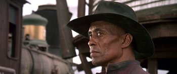 Movie still from “Once Upon a Time in the West” (1968), directed by Sergio Leone – An older man wearing a green hat looking to his left; Close Up shot, Low angle