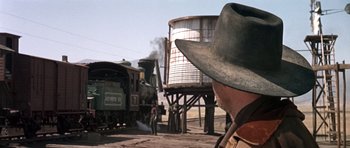 Movie still from “Once Upon a Time in the West” (1968), directed by Sergio Leone – A man standing next to a train on a train track; Wide shot, Low angle