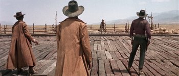 Movie still from “Once Upon a Time in the West” (1968), directed by Sergio Leone – A man wearing a long coat and a cowboy hat; Wide shot, Low angle