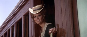 Movie still from “Once Upon a Time in the West” (1968), directed by Sergio Leone – A woman wearing a cowboy hat standing next to a door; Close Up shot, Low angle