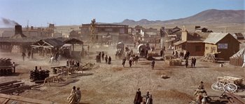 Movie still from “Once Upon a Time in the West” (1968), directed by Sergio Leone – A group of people standing on top of a dirt field; Extreme Wide shot, High angle