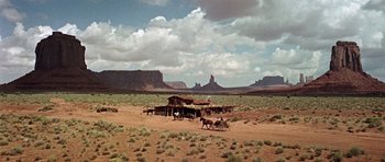 Movie still from “Once Upon a Time in the West” (1968), directed by Sergio Leone – An old western style building with horses in the background; Extreme Wide shot, Low angle