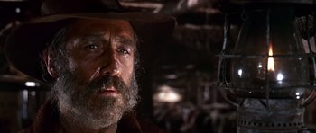 Movie still from “Once Upon a Time in the West” (1968), directed by Sergio Leone – An old man with a beard wearing a cowboy hat; Close Up shot, Low angle