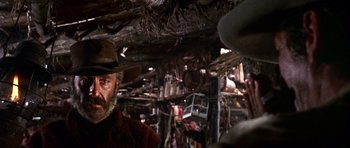 Movie still from “Once Upon a Time in the West” (1968), directed by Sergio Leone – A man in a cowboy hat standing next to a tree; Close Up shot, Over the shoulder angle