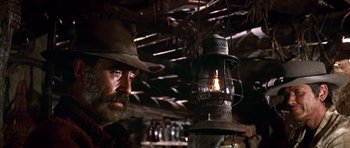 Movie still from “Once Upon a Time in the West” (1968), directed by Sergio Leone – A man with a hat and a beard is standing next to a lantern; Close Up shot, Low angle