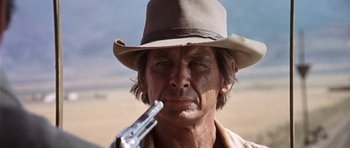 Movie still from “Once Upon a Time in the West” (1968), directed by Sergio Leone – A man with a hat and a gun in his mouth; Close Up shot, Low angle