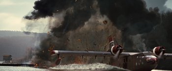 Movie still from “The Expendables 2” (2012), directed by Simon West – An airplane flying through the air on a cloudy day; Wide shot, High angle