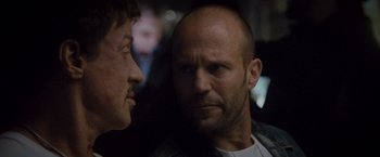 Movie still from “The Expendables 2” (2012), directed by Simon West – A man with a shaved head is looking at another man with a shaved head; Close Up shot, Over the shoulder angle