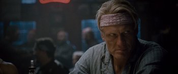 Movie still from “The Expendables 2” (2012), directed by Simon West – A person wearing a headband; Close Up shot, Over the shoulder angle