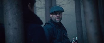 Movie still from “The Expendables 2” (2012), directed by Simon West – A man wearing a hat standing next to another man; Close Up shot, Over the shoulder angle